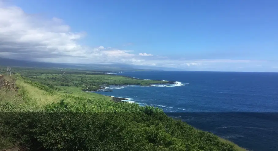Wide coastal view of the Kaʻū coastline on the Big Island of Hawaiʻi, with green cliffs meeting the Pacific Ocean.