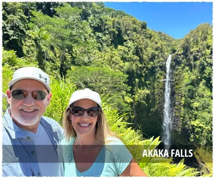 Couple standing near ʻAkaka Falls surrounded by rainforest